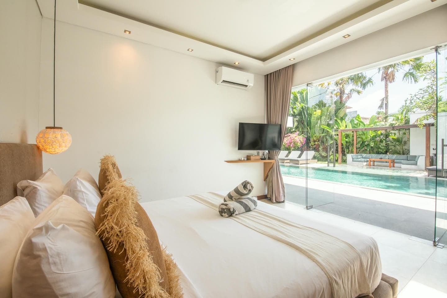 Villa Niko Dua — bedroom with floor-to-ceiling glass onto the pool